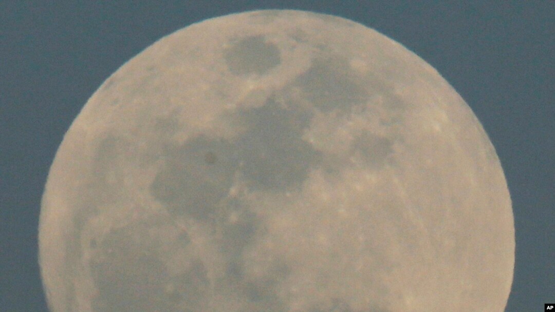 An Alaska Airlines flight passes by the rising moon, Feb. 21, 2016, in Phoenix. 
