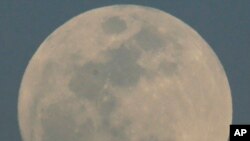 An Alaska Airlines flight passes by the rising moon, Feb. 21, 2016, in Phoenix. 