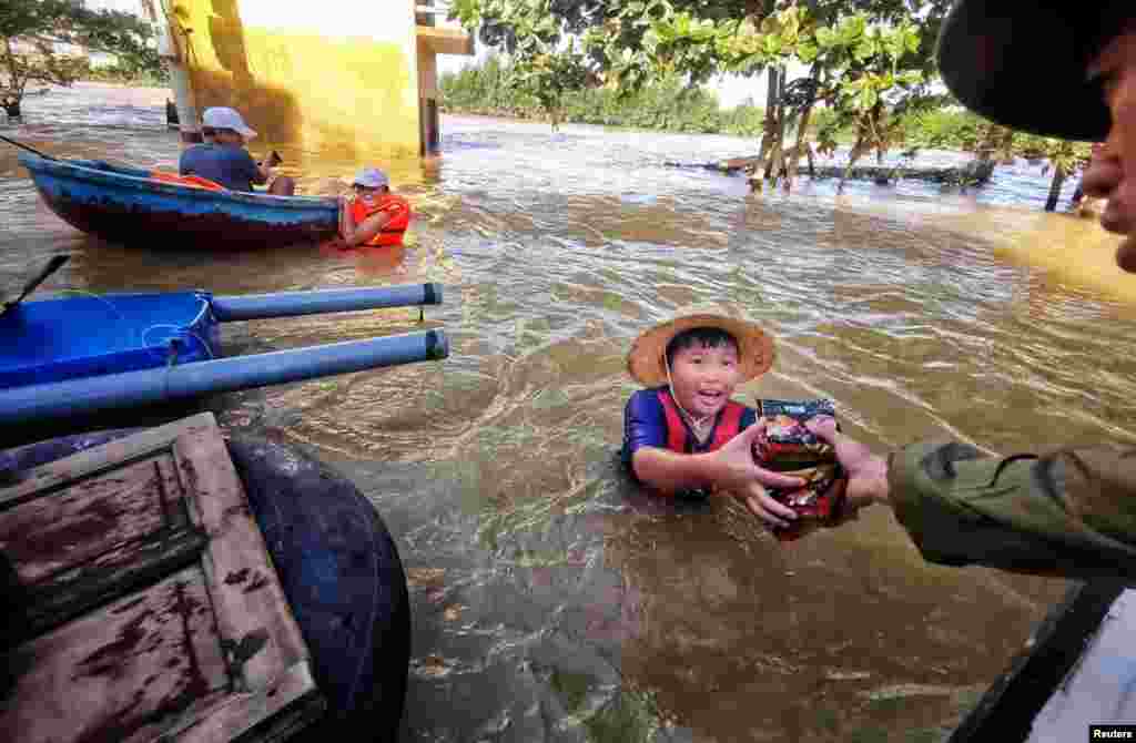 A boy gets food donation from a volunteer at a flooded area in Quang Binh province, Vietnam, Oct. 22, 2020. (Reuters)