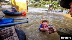A boy gets food donation from a volunteer at a flooded area in Quang Binh province, Vietnam, Oct. 22, 2020. (Reuters)
