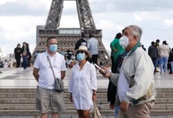 People wearing protective masks stand at the Trocadero square near the Eiffel Tower as France reinforces mask-wearing as part of efforts to curb a resurgence of the coronavirus disease across the country, in Paris, France, Aug. 28, 2020.