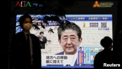 A pedestrian wearing a protective mask walks past a large screen on a building showing Japan's Prime Minister Shinzo Abe declaring a state of emergency, following the coronavirus disease (COVID-19) outbreak, in Tokyo, Japan April 7, 2020. REUTERS…