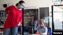 A teacher checks a student's work as students return to school as coronavirus disease (COVID-19) restrictions are lifted in Philadelphia, Pennsylvania, U.S., March 8, 2021. 