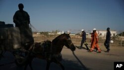 FILE—Workers walk toward a local hotel after arriving from the offshore gas terminal in Saint Louis, Senegal, January 20, 2023. Senegalese officials and the gas companies say people should be patient, as jobs and benefits from the gas deal will materialize.