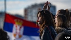 Studentkinja na protestnoj blokadi Autokomande, dok se srpska zastava vijori u pozadini (Foto: AFP/Andrej ISAKOVIC)