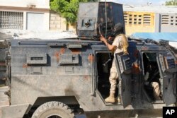 FILE — Police take cover during an anti-gang operation in Port-au-Prince, Haiti, March 1, 2024.