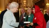 Pakistani teenage activist Malala Yousafzai gives a copy of her book "I am Malala", to Britain's Queen Elizabeth during a Reception for youth, education and the Commonwealth at Buckingham Palace in London.
