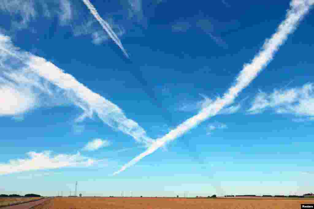 Airplane traces are pictured in a blue sky, in Caen, France. 