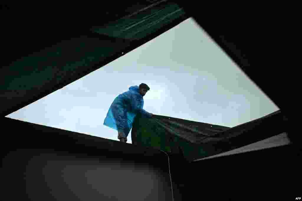 یک رضاکار، حین پوشاندن سقف یک پناهگاه برای نجات یافتگان رویداد لغزش زمین در ایالت کرالا در هند &nbsp;