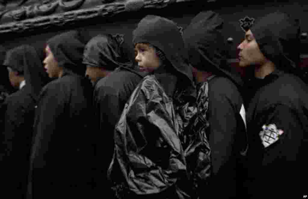 Penitents, one of them carrying a child, participate in a Holy Week procession on Good Friday in Antigua Guatemala, Guatemala, Friday April 6, 2012. Holy Week commemorates the last week of the life of Jesus, culminating in his crucifixion on Good Friday a