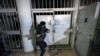 A man breaks the lock of a cell in the infamous Saydnaya military prison, just north of Damascus, Syria, Dec. 9, 2024.