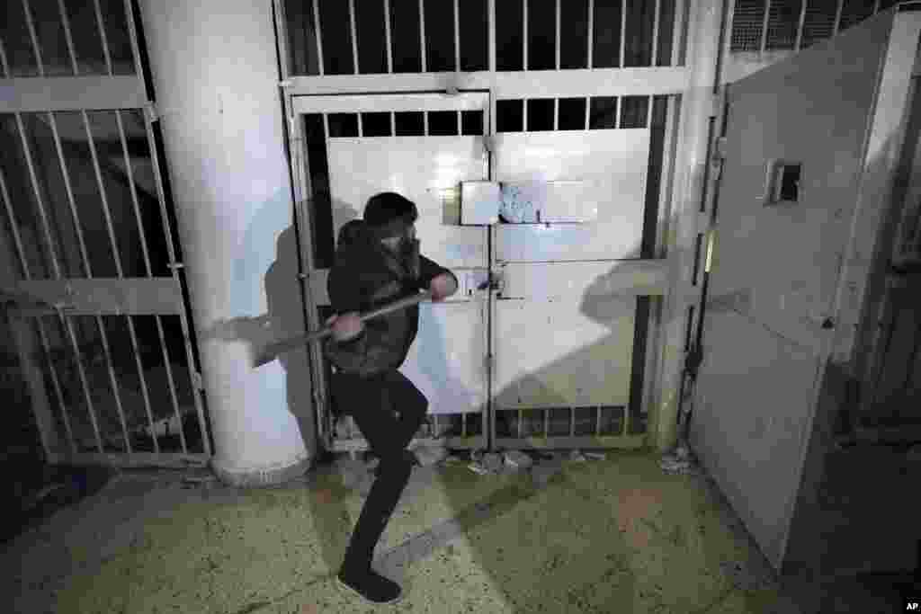 A man breaks the lock of a cell in the infamous Saydnaya military prison, just north of Damascus, Syria, Dec. 9, 2024.