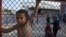 A child stands behind a fence during a protest against the living conditions at the Oreokastro camp, near the northern town of Thessaloniki, Greece, June 25, 2016.