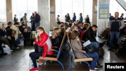 Passengers sit with their luggage while waiting for trains at the central railway station in Kyiv, Ukraine, April 19, 2016. 