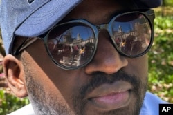 FILE—Guinean Diogo Diallo poses for a photo as City hall is reflected in his sunglasses in New York on Tuesday, April 16, 2024.