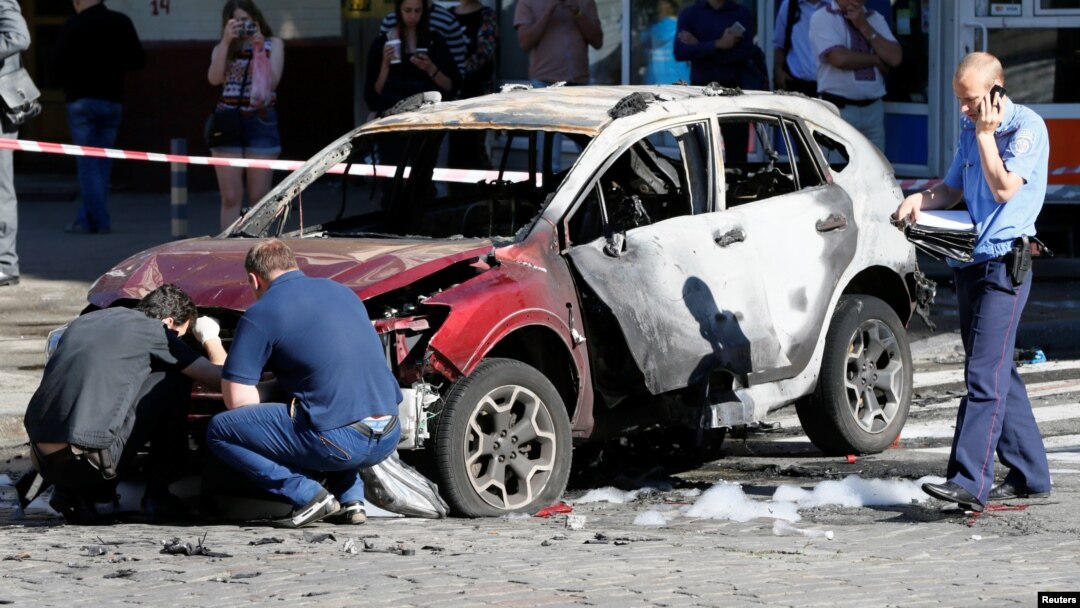 Investigators inspect a damaged car at the site where journalist Pavel Sheremet was killed by a car bomb in central Kyiv, Ukraine, July 20, 2016.