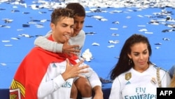 Cristiano Ronaldo berpose dengan pasangannya, Georgina Rodriguez dan putranya Cristiano Jr, setelah Real Madrid memenangkan laga final Liga Champion, melawan Liverpool di Stadion Olympic di Kiev, Ukraina, 26 Mei 2018.