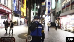A police officer asks people to refrain from going out after 8 p.m. in the Shinjuku area of Tokyo on Jan. 8, 2021 during the first day under a state of emergency over the coronavirus pandemic. 
