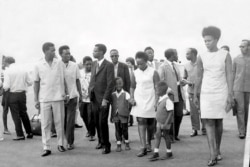 FILE - Godefroid Nyilibakwe, at center with his wife and two of his children, talks with two other Rwandan officials at Kigali’s airport in this undated photo. Like Nyilibakwe, the two – Andre Bizimana and Frodouald Minani – died in prison.