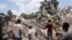 FILE - People search through the rubble of what used to be the Manguier Hotel after the earthquake hit on August 14, 2021 in Les Cayes, southwest Haiti.