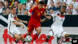 Joueur de l’équipe allemande, Jerome Boateng, à droite, et son co-équipier, Philipp Lahm, à gauche, se discutent une balle avec Gevorg Chazaryan de l’Arménie, au centre, lors d'un match amical de football entre l'Allemagne et l'Arménie dans l'arène Coface à Mayence, Allemagne, 6 juin, 2014. (AP Photo / Michael Probst)