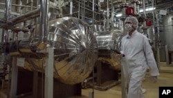 FILE - An Iranian security official in protective clothing walks through part of the Uranium Conversion Facility just outside the Iranian city of Isfahan.