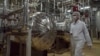 FILE - An Iranian security official in protective clothing walks through part of the Uranium Conversion Facility just outside the Iranian city of Isfahan.