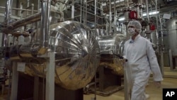 FILE - An Iranian security official in protective clothing walks through part of the Uranium Conversion Facility just outside the Iranian city of Isfahan.