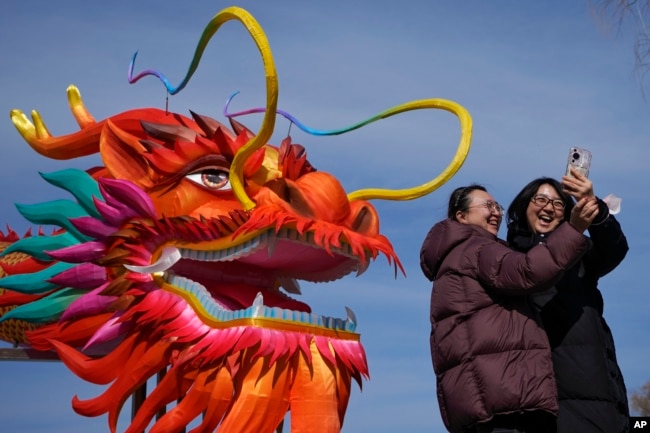 北京后海迎接龙年到来的巨龙装饰前两名女子在自拍。(2024年2月8日)