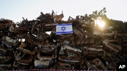 Izraelska zastava istaknuta na gomilu ugljenisanih vozila koja su bila spaljena tokom krvavog napada militanata Hamasa na Izrael 7. oktobra, ispred grada Netivota, južni Izrael, 7. januara 2024. 