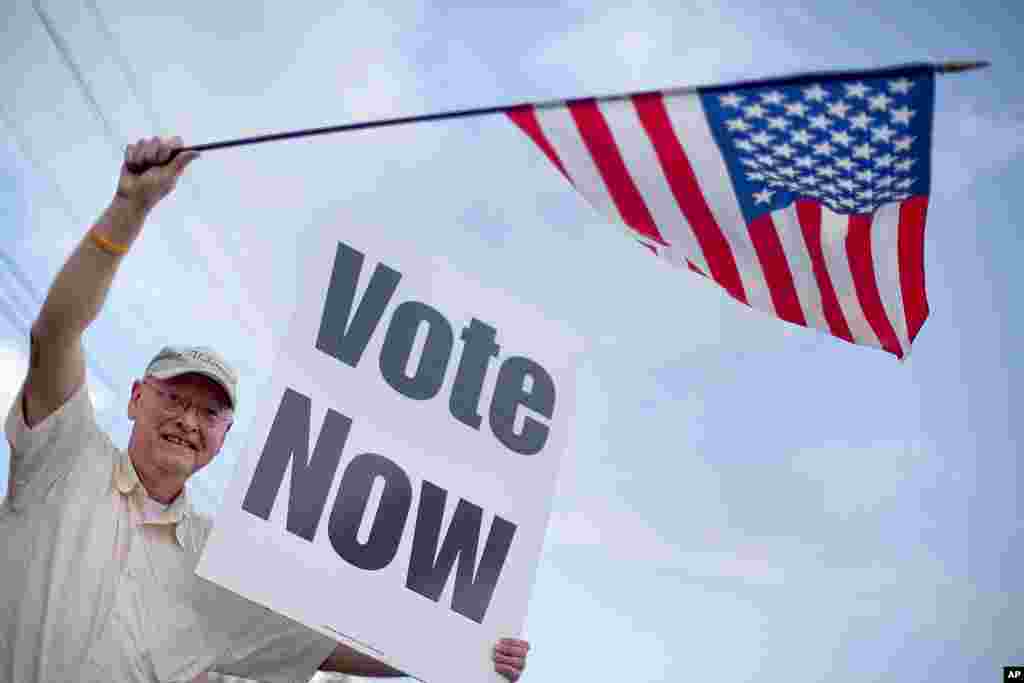 Danny Cooper, of Chilton County, waves to motorists outside a polling place, March 13, 2012, in Vestavia Hills, Alabama. (AP)