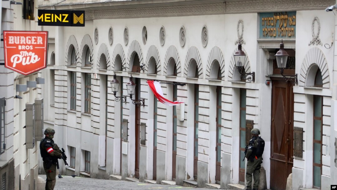 Un hombre lleva una corona de flores mientras pasa junto a los agentes de policía en Viena, Austria, el martes 3 de noviembre de 2020.