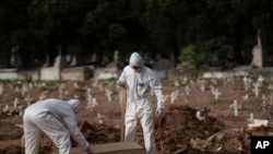 Cemetery workers in protective clothing bury the coffin of 57-year-old Paulo Jose da Silva, who died from the new coronavirus, in Rio de Janeiro, Brazil, June 5, 2020. 