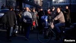 A man cycles past security personnel, and uniformed and plainclothes police, who are standing outside the entrance to a government building where petitioners congregate daily to protest private equity scams, in central Beijing, October 22, 2012.