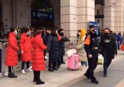 In this image made from video, security officials turn away a traveler at an entrance to the Hankou Railway Station in Wuhan in central China's Hubei Province, Jan. 23, 2020.
