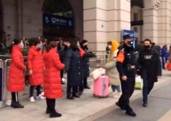 In this image made from video, security officials turn away a traveler at an entrance to the Hankou Railway Station in Wuhan in central China's Hubei Province, Jan. 23, 2020.