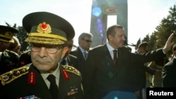 FILE - Turkish Prime Minister Tayyip Erdogan, flanked by Turkish Chief of Staff General Hilmi Ozkok (L) waves as they walk past the Turkish war memorial in Gallipoli, in western Turkey.