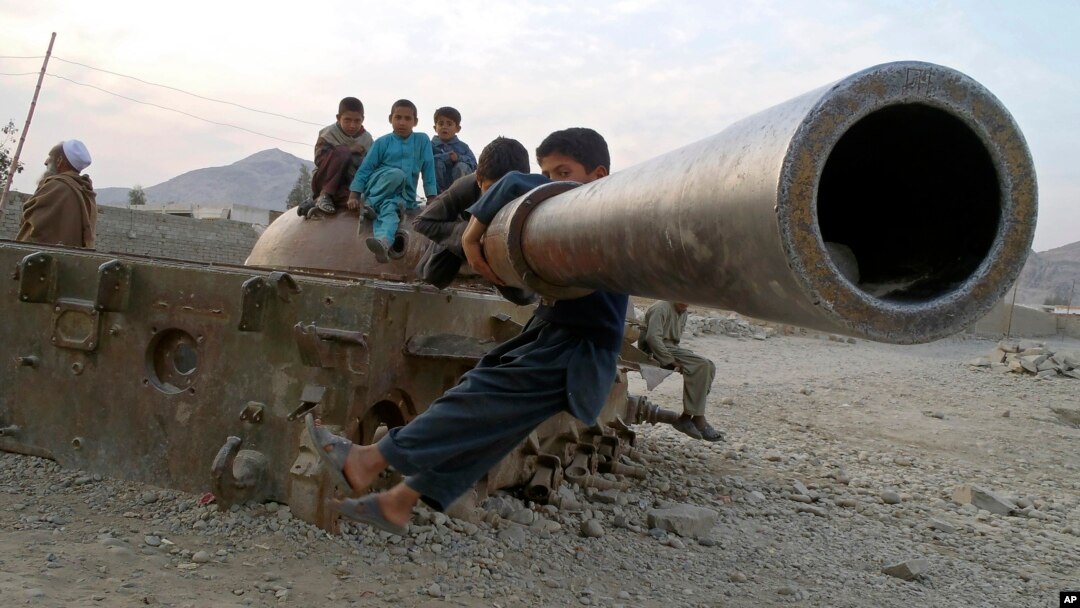FILE - Afghan children play on the remains of a Soviet tank in the Behsood district of Jalalabad, Afghanistan, Feb 18, 2013. 