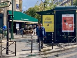 A man crosses the street near Paris' Parmentier metro station - mask half down, although it is required in this area. (Lisa Bryant/VOA)