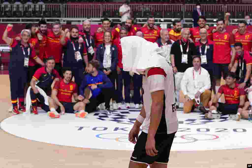 Egypt&#39;s Ahmed Mohamed, center, walks as Spain&#39;s team members celebrate after the men&#39;s bronze medal match handball match between Egypt and Spain at the 2020 Summer Olympics, Saturday, Aug. 7, 2021, in Tokyo, Japan. (AP Photo/Pavel Golovkin)