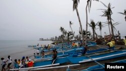 FILE - Homeless typhoon victims gather near their new fishing boats given by a religious organization along a coastal village devastated by super Typhoon Haiyan in Tacloban city, central Philippines.