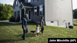 Joyce Lilly, right, holds her granddaughter Paige's hand alongside her husband, Anil, and dog Max at their new home, Tuesday, July 21, 2020, in Washingtonville, New York.