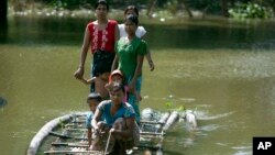 Flood victims ride a bamboo raft over a flooded road to receive relief items from private donors in Thabaung township, Ayeyarwaddy delta, Myanmar, Aug. 29, 2015.