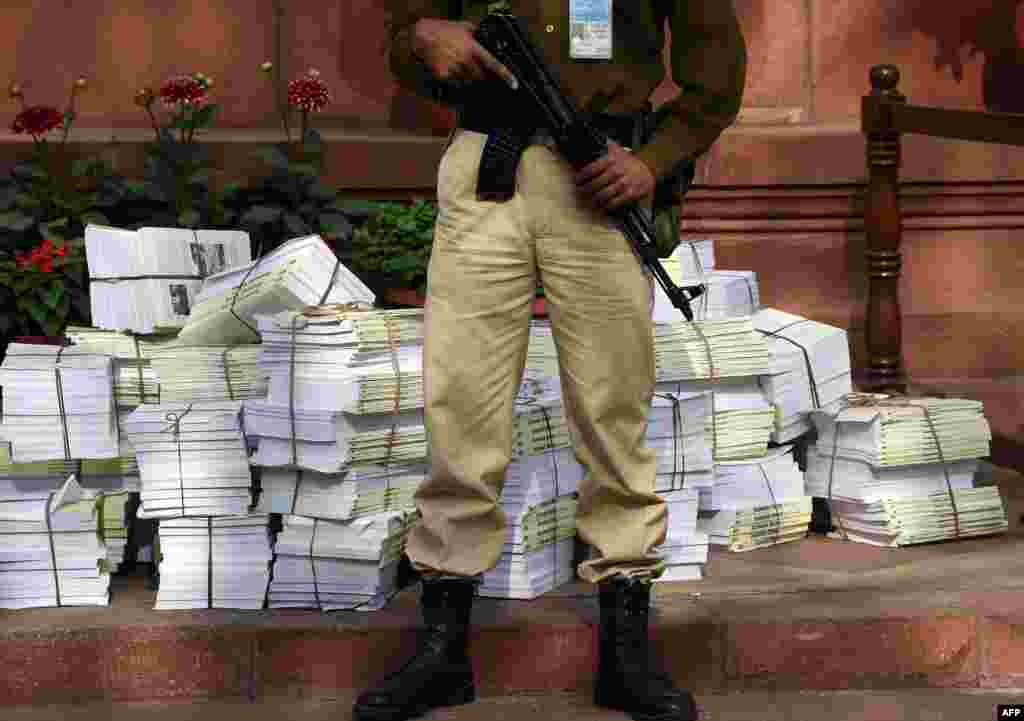 An Indian security personnel stands guard stands in front of copies of the &quot;Economic Survey 2014-15&quot; at Parliament House in New Delhi.