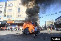 Seorang anak laki-laki Palestina berdiri dekat kendaraan militer Israel yang terbakar setelah orang-orang bersenjata Palestina menyusup ke wilayah yang dikuasai Israel di utara Jalur Gaza, 7 Oktober 2023. (Foto: Mahmoud Issa/Reuters)