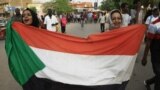 FILE - Sudanese women march with a national flag during a rally in the capital Khartoum, June 30, 2019. 