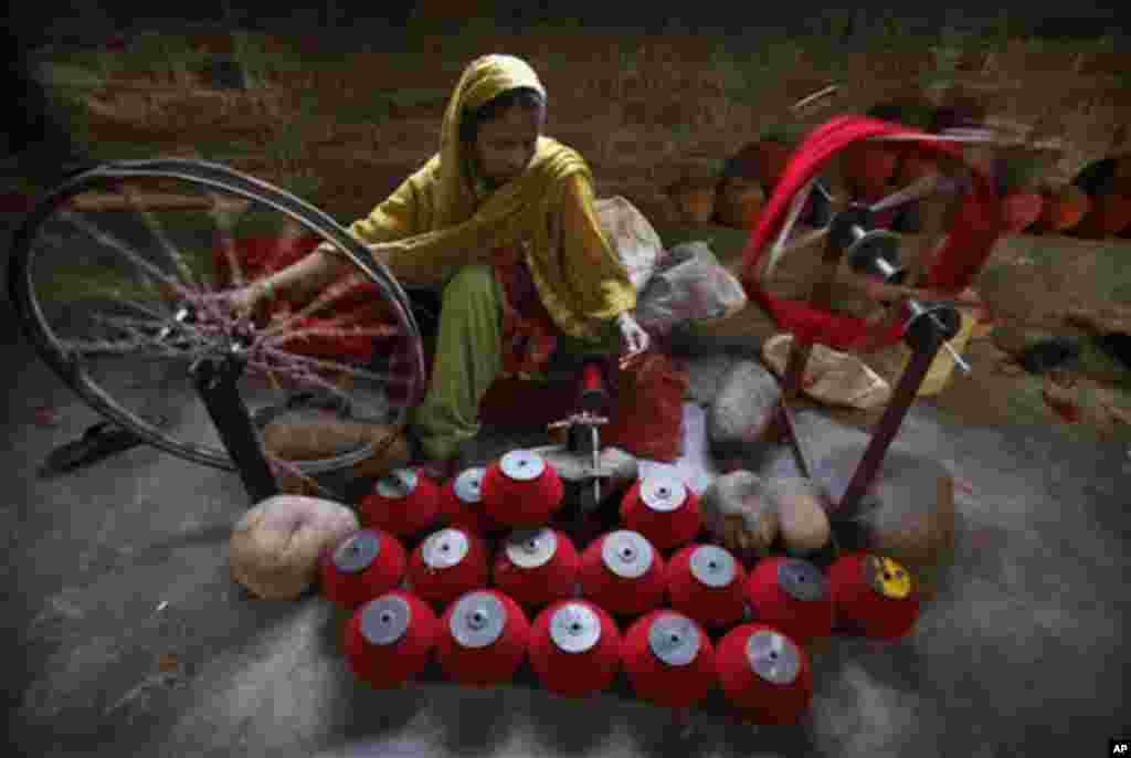 An Indian worker spins thread for use in making carpets at a factory on the outskirts of Jammu, India, Friday, March 16, 2012. Carpet weaving is believed to have been brought to India by the Mughal Emperor Akbar in the 16th century. A recent economic surv