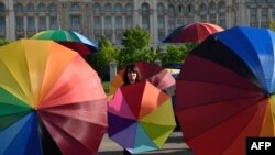 People hold rainbow umbrellas to celebrate International Day Against Homophobia, Biphobia and Transphobia in the front of the Romanian Parliament building in Bucharest, May 17, 2016. 