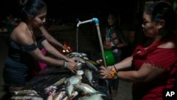 Juma Indigenous women prepare the day’s catch in their community, near Canutama, Amazonas state, Brazil, July 8, 2023.