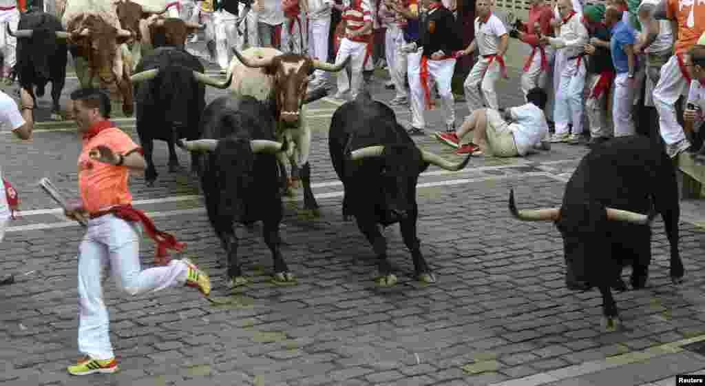 Runners sprint alongside Valdefresno fighting bulls at the Estafeta corner during the third running of the bulls of the San Fermin festival in Pamplona July 9, 2013. Two runners were treated in hospital for bruising following the run that lasted two minut